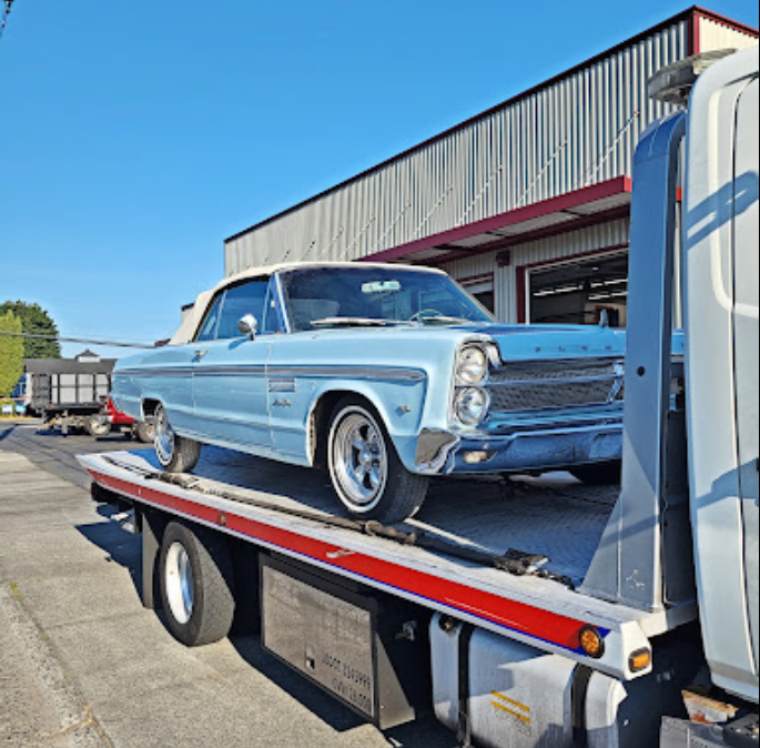 Classic muscle car being towed on a rollback tow truck in Kirkland, WA.